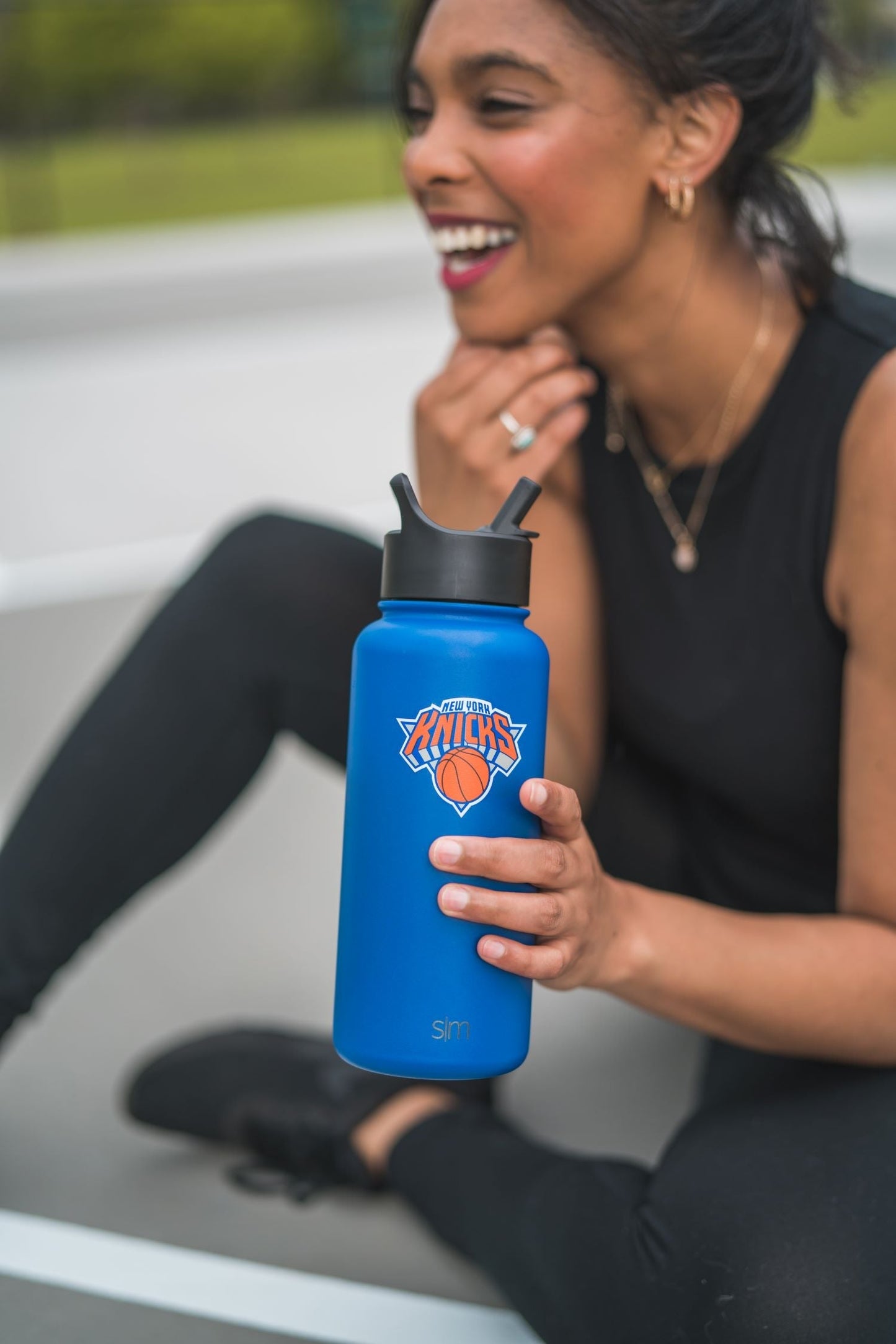 Royal blue water bottle with black lid and accents held by person in athletic wear