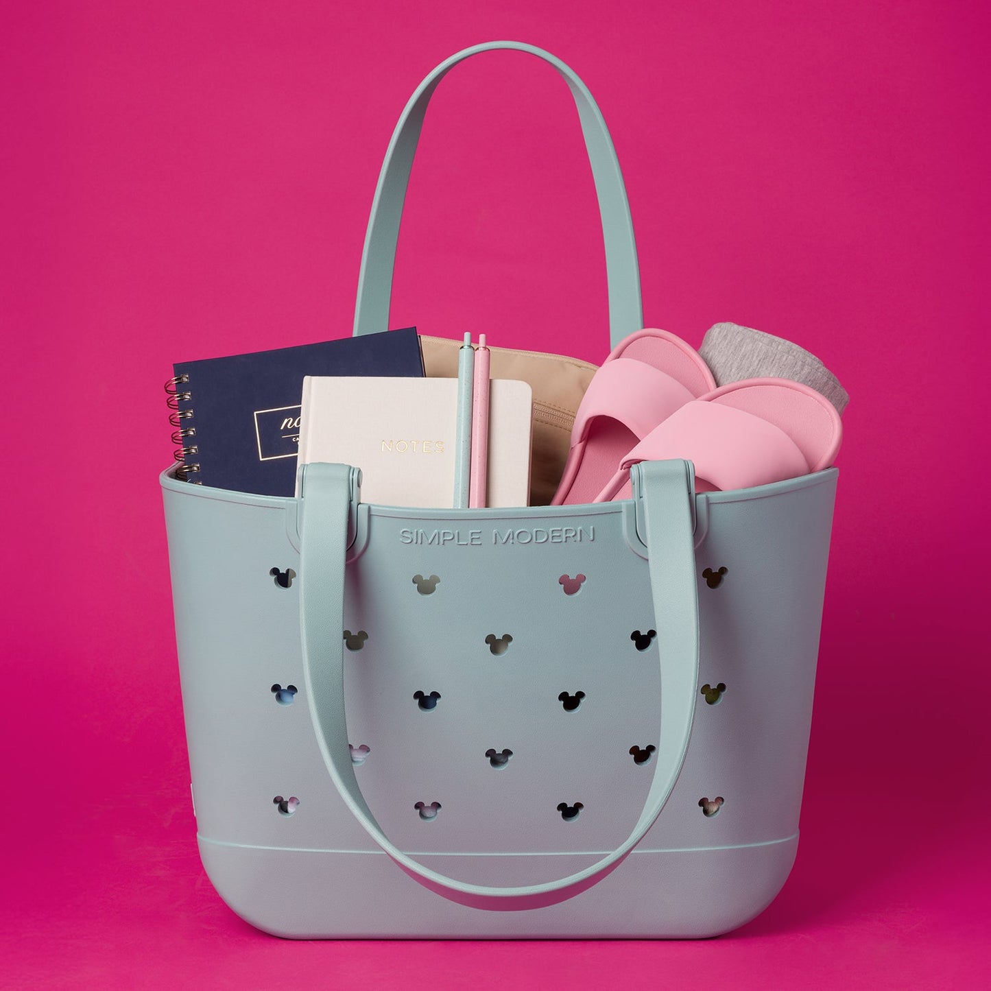 Pale blue-gray tote bag displayed against a vibrant hot pink background