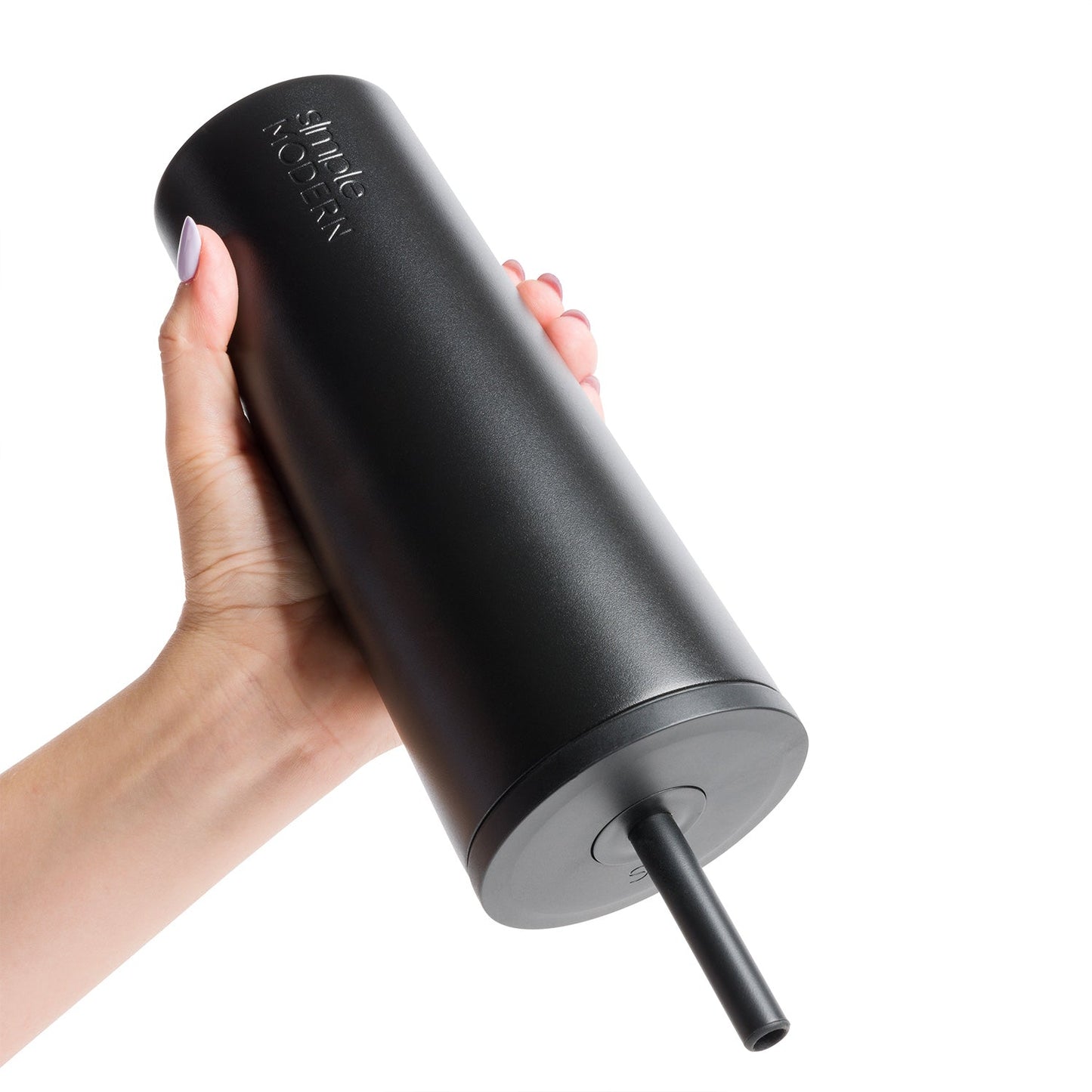 Matte black tumbler with charcoal gray base and straw held in hand against black background
