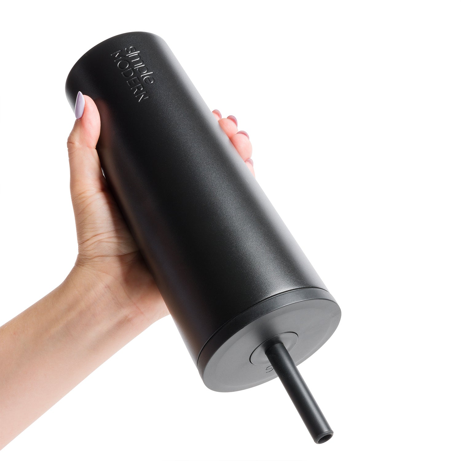 Matte black tumbler with charcoal gray base and straw held in hand against black background