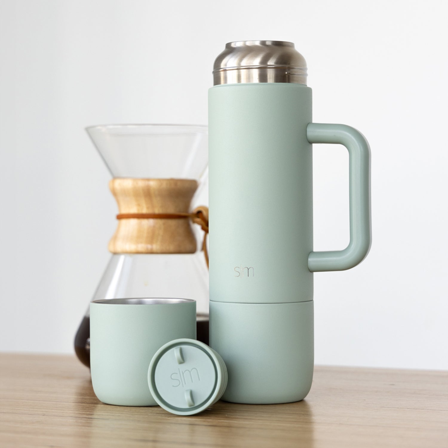 Simple Modern branded products in soft sage green displayed with warm natural wood tones